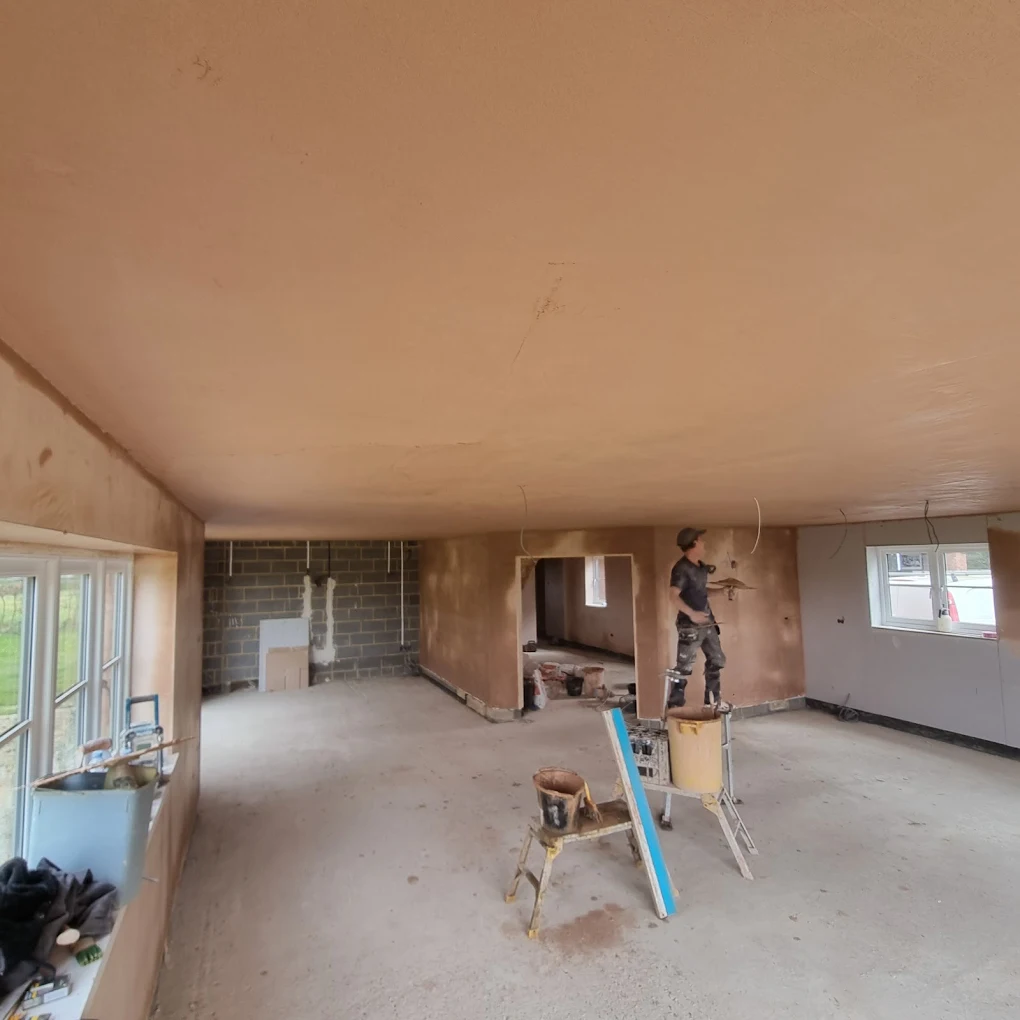 Plasterer applying a fresh finish coat to an open-plan interior